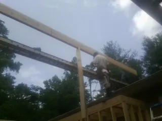 Carpenter setting a ridge beam over a new addition frame — Ice Dam Removal by Roofing Brothers in Bowersville
