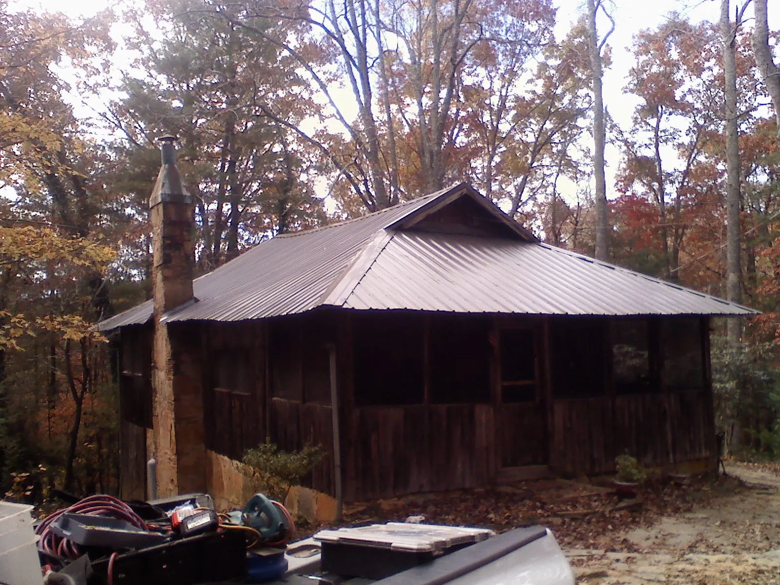 Brown metal hip roof on an old cabin with a stone chimney in Bowersville