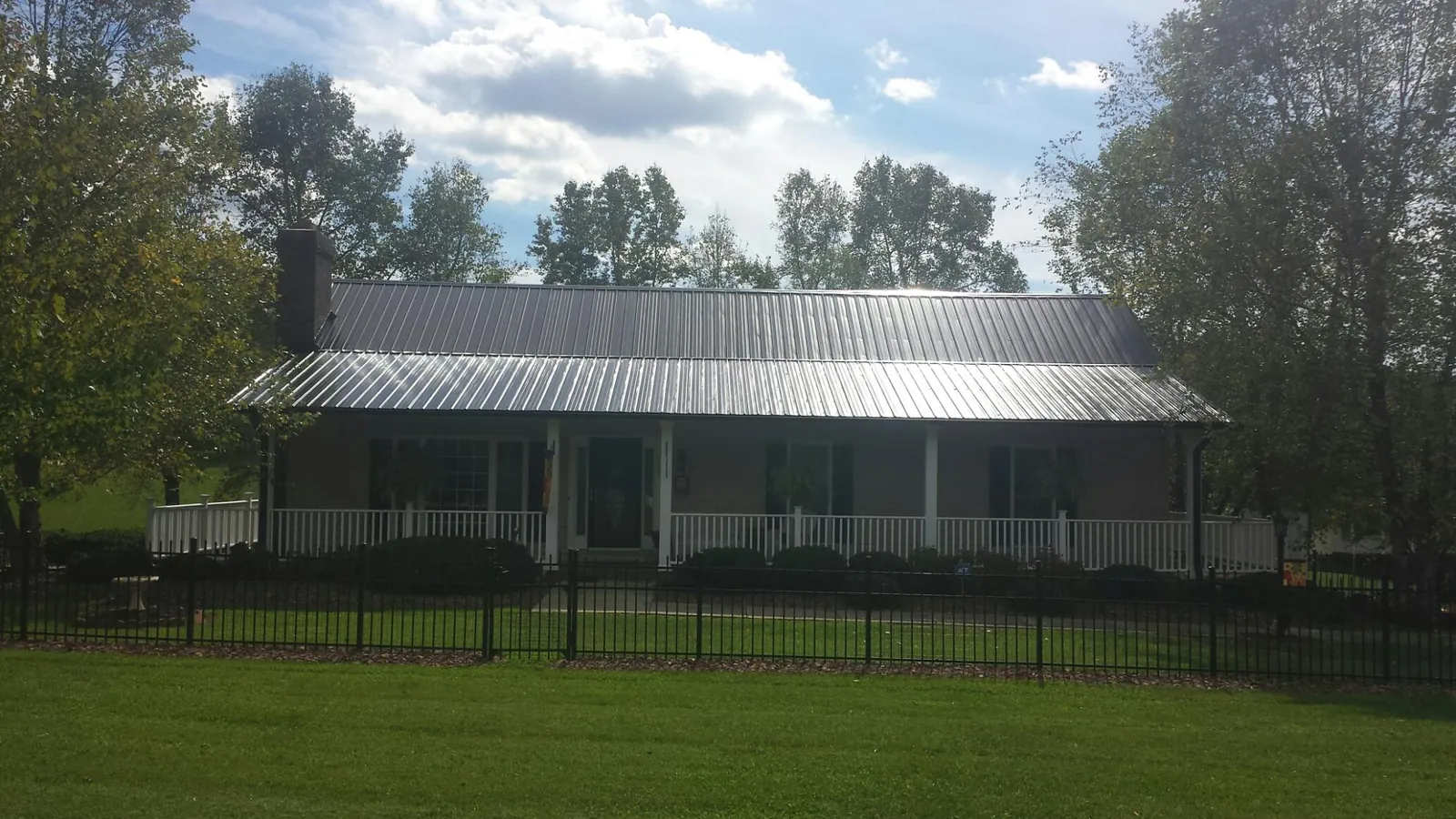 Gray metal roof on a brick ranch with a full width front porch — Gutter Guard Installation work by our crew in Bowersville