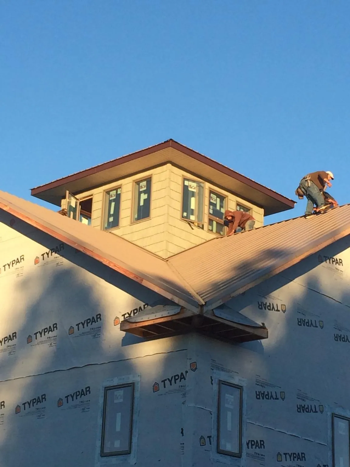 Roofers working around a rooftop cupola on a new metal roof at sunset — Roof Waterproofing in Bowersville by Roofing Brothers